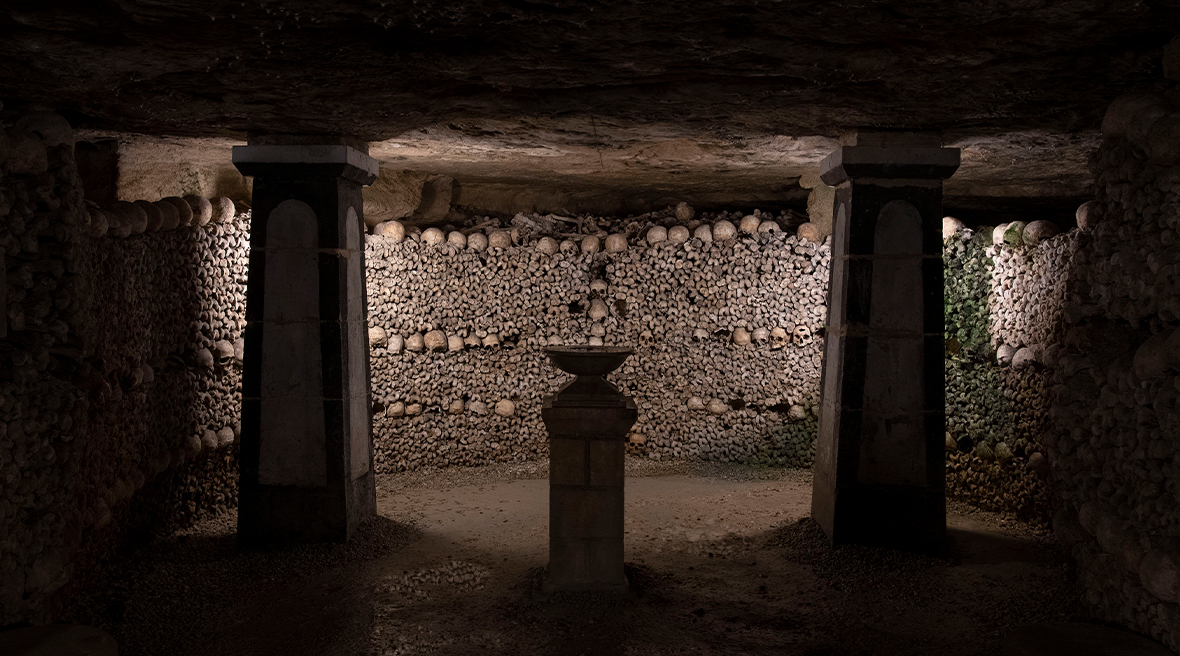 A dimly lit underground chamber whose walls are lined with thousands of skulls and bones